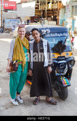 DARAW, EGYPT - FEBRUARY 6, 2016: Tourist posing with the driver of Tuk-tuk vehicle on the street. Stock Photo