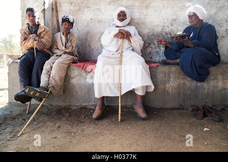 DARAW, EGYPT - FEBRUARY 6, 2016: Group of local camel salesmen resting on the wall. Stock Photo