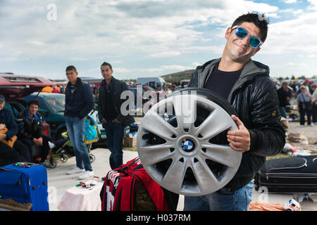 ZAGREB, CROATIA - OCTOBER 20, 2013: Roma salesman holding used car rim at Zagreb's flea market Hrelic. Stock Photo