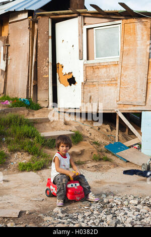ZAGREB, CROATIA - OCTOBER 21, 2013: Cute little Roma boy sitting on toy car at street. Stock Photo
