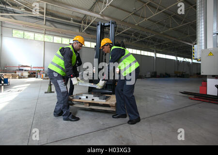 Workers taking aluminium billet at CNC machine shop Stock Photo