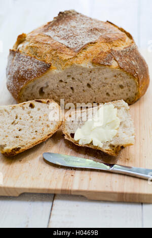 A slice of bread and butter cut from a freshly baked homemade sourdough loaf. Stock Photo