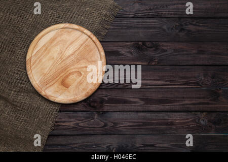 Round cutting board on dark wooden table Stock Photo