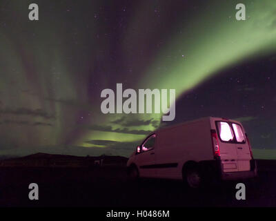 Amazing View of Aurora Borealis Dancing on the Winter Night sky over our White Camper Van, Iceland Stock Photo
