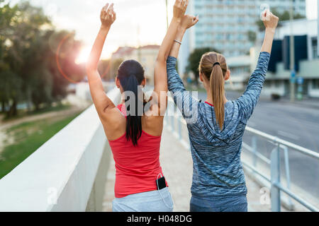 Two women happy after finishing exercises and lifting their hands Stock Photo