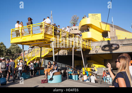 Crowds of people enjoying the sun outside the Royal Festival Hall on the Southbank of the Thames in London. Stock Photo