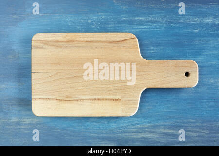 Empty wooden cutting board on rustic blue table, background with space for text, top view. Stock Photo