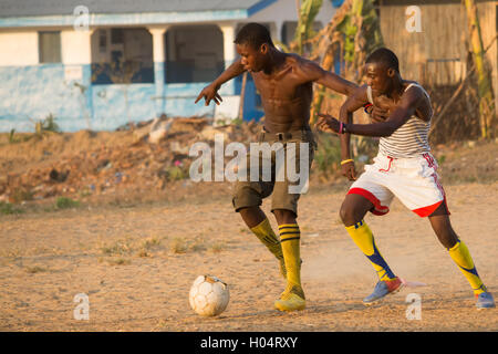Two young men playing soccer / football in African village with tattered old ball Stock Photo