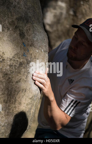 Man bouldering in Fontainebleau Forest, France. Climbing on a boulder. Natural light, hand in focus. Active, sport. Stock Photo