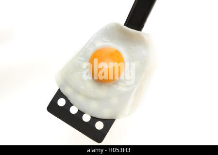 Fried egg on the black spatula, ready to be served. White background. Stock Photo