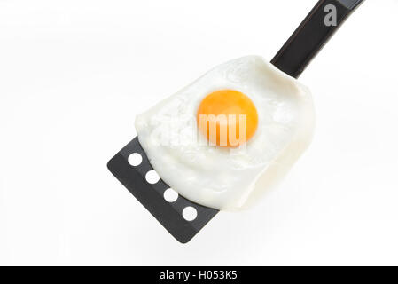 Fried egg on the spatula, ready to be served. White background. Stock Photo