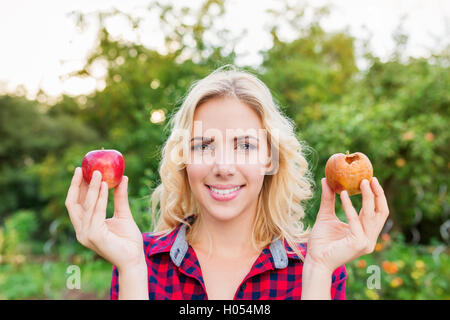 Beautiful woman holding rotten and good apple Stock Photo
