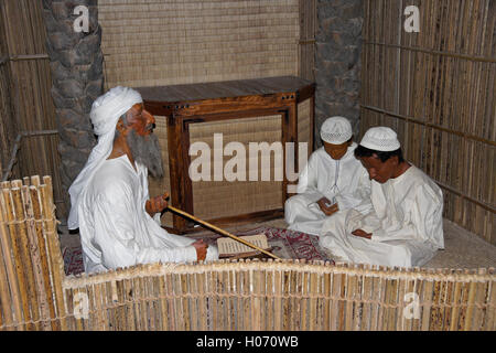 Teacher and students learning the Koran, exhibit in Hatta Heritage Village, Dubai, United Arab Emirates Stock Photo