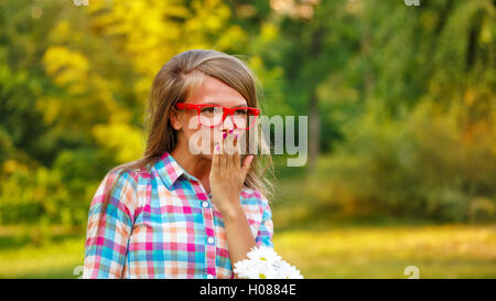 Young woman sends a kiss in a public park. Flirt. Outdoor Activities on a sunny day. Stock Photo