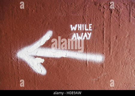 Arrow on a wall with text, detail of an indication, while away Stock Photo
