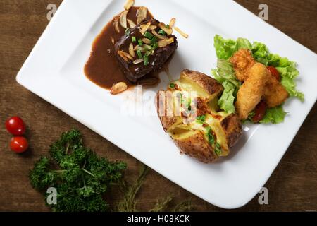 Stewed beef and fried fish with potato on white dish Stock Photo