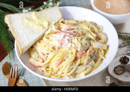 Simple bowl of chinese noodle with sandwich on the table Stock Photo