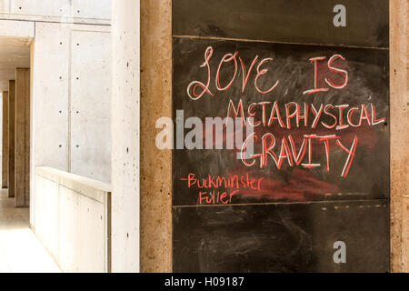 Quote: "love is metaphysical gravity" by Buckminster Fuller on blackboard wall of a building. Stock Photo