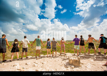 Group of people hold hands at the summit of Nohoch Mul Pyramid in the Ancient Mayan City of Coba, outside Tulum, Mexico Stock Photo