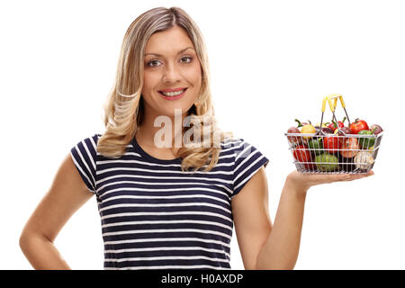 Happy woman holding a small shopping basket full of fruits and vegetables isolated on white background Stock Photo