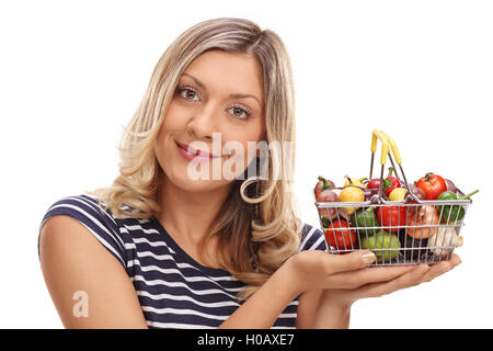 Joyful woman holding a small shopping basket full of vegetables and fruits isolated on white background Stock Photo