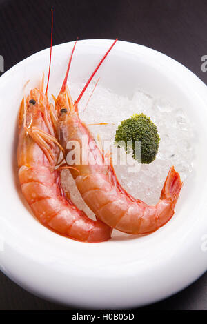 Steamed shrimps on ice on white plate with broccoli Stock Photo