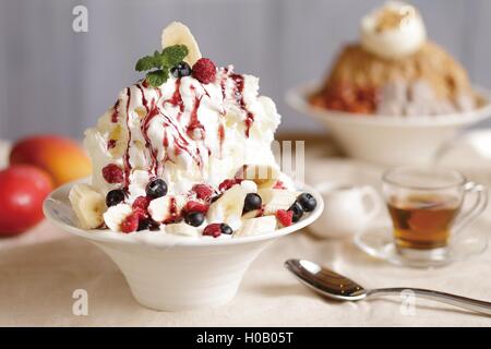 Cream with banana and cherry on cupcake on the table with tea cup Stock Photo
