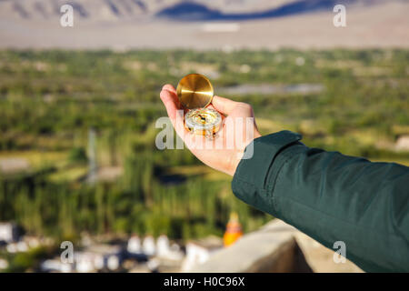 Young traveler looking at compass in Himalaya mountain view background (Focus on compass) Stock Photo