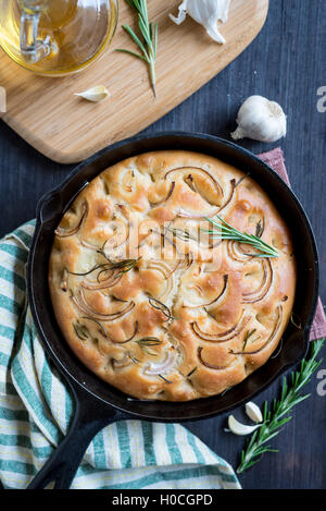 No knead roasted garlic and rosemary focaccia cake in black pan Stock Photo