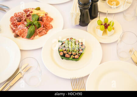 Beautifully decorated catering banquet table with different food snacks and appetizers with sandwich, caviar, fresh fruits on co Stock Photo