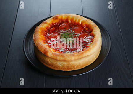 Chicago style of pizza with red chili on black plate Stock Photo