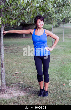 Asian American woman leaning against a tree Stock Photo