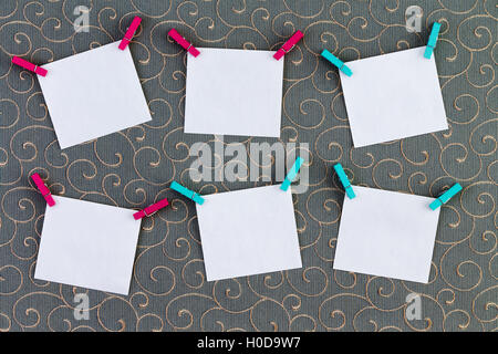 Six crooked tags with clothespins attached on top corners over cotton thread gray background Stock Photo