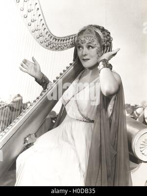 Woman in ancient Greek costume playing harp Stock Photo