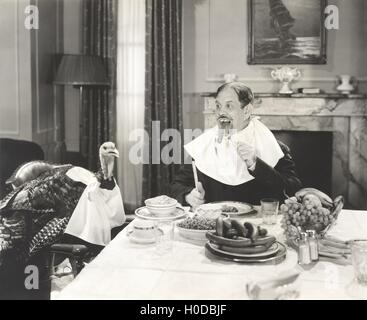 Man and his pet turkey sitting down to an untraditonal Thanksgiving dinner Stock Photo