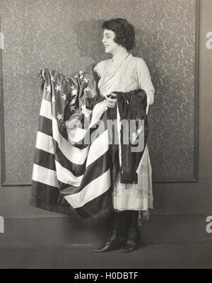 Woman with draped American flag over her arms Stock Photo
