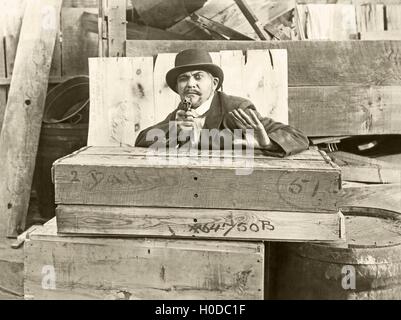 Cornered man behind wooden crates pointing gun Stock Photo