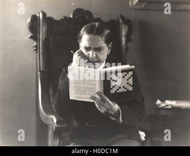 Man closely studying a crossword puzzle book Stock Photo