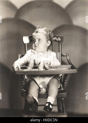 Cute baby sitting on high chair Stock Photo