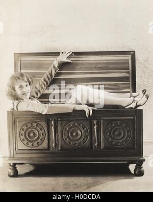 Woman sitting in wooden chest Stock Photo