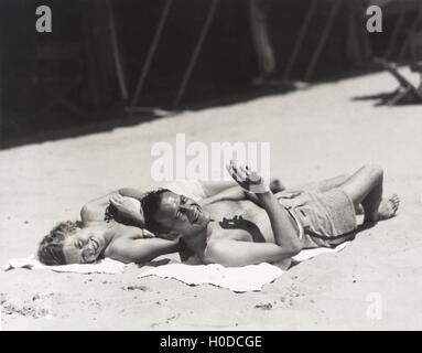 Happy couple sunbathing on beach Stock Photo
