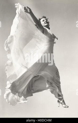Low angle view of woman in gown jumping in mid-air Stock Photo