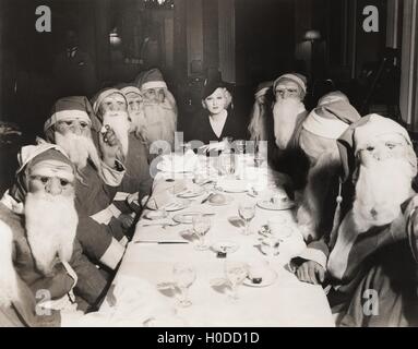 Woman lunching with twelve Santa Clauses Stock Photo