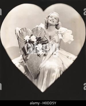 Woman holding a heart-shaped box Stock Photo