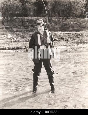 Fisherman in waders fishing in river Stock Photo