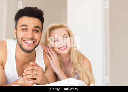 Young Couple Lying In Bed, Happy Smile Hispanic Man And Woman Stock Photo
