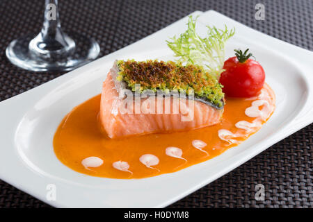 Baked Salmon filled with herbs in Lobster sauce and tomato, lettuce on white plate Stock Photo