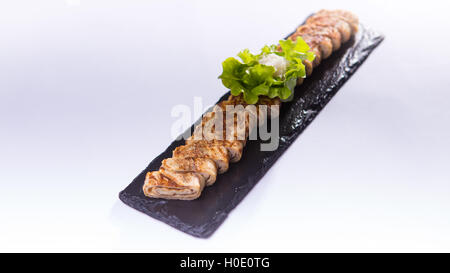 Sliced pork rolls with herbs on black rock plate Stock Photo