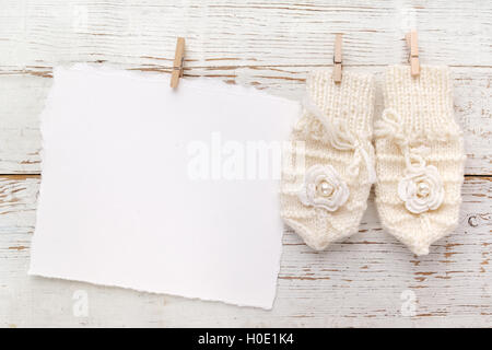 New Born or baptism Greeting Card. Blank with baby girl gloves on white wooden background Stock Photo