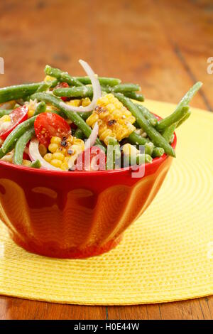 Grilled corn and green bean salad on red bowl in restaurant Stock Photo